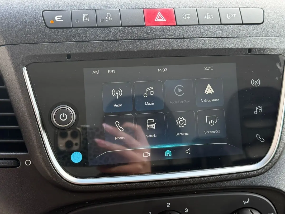 Gros plan sur l'écran tactile central noir du tableau de bord de l'Iveco Daily blanc, avec boutons de commande et interface multimédia.