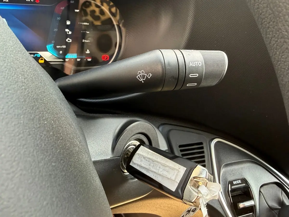Gros plan sur la clé insérée dans le contacteur du tableau de bord noir de l’Iveco Daily blanc, avec commande d’essuie-glace visible.