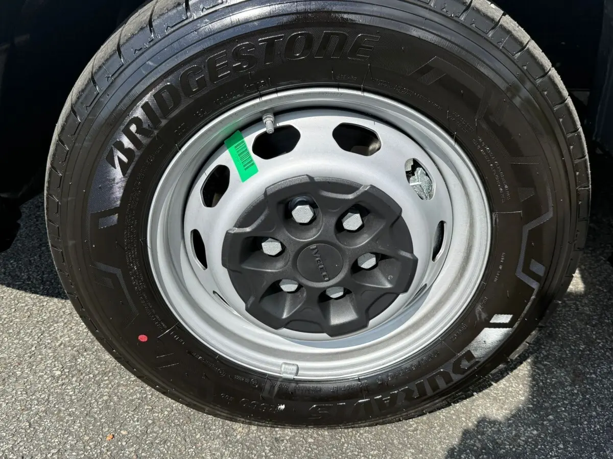 Gros plan sur la roue avant droite d’un Iveco Daily blanc 2026 avec jante acier grise et pneu Bridgestone noir.