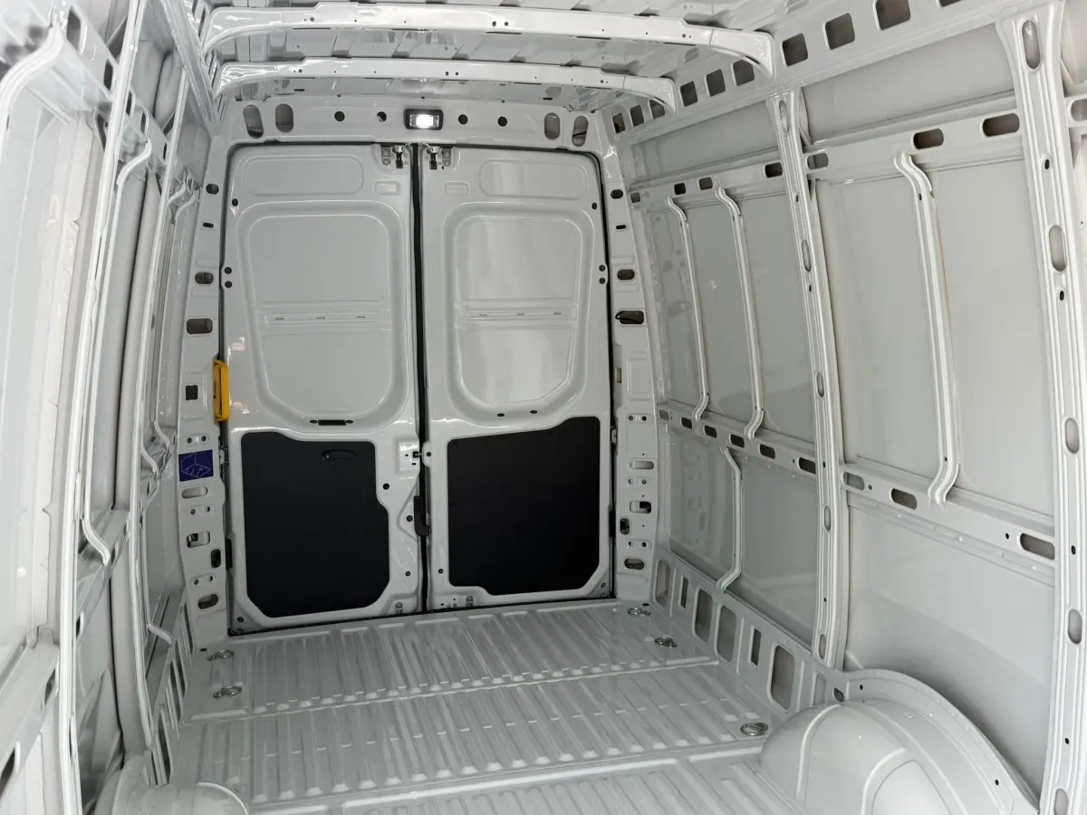 Vue intérieure arrière du fourgon Iveco Daily blanc 2026, montrant l’espace de chargement vide et les portes battantes.