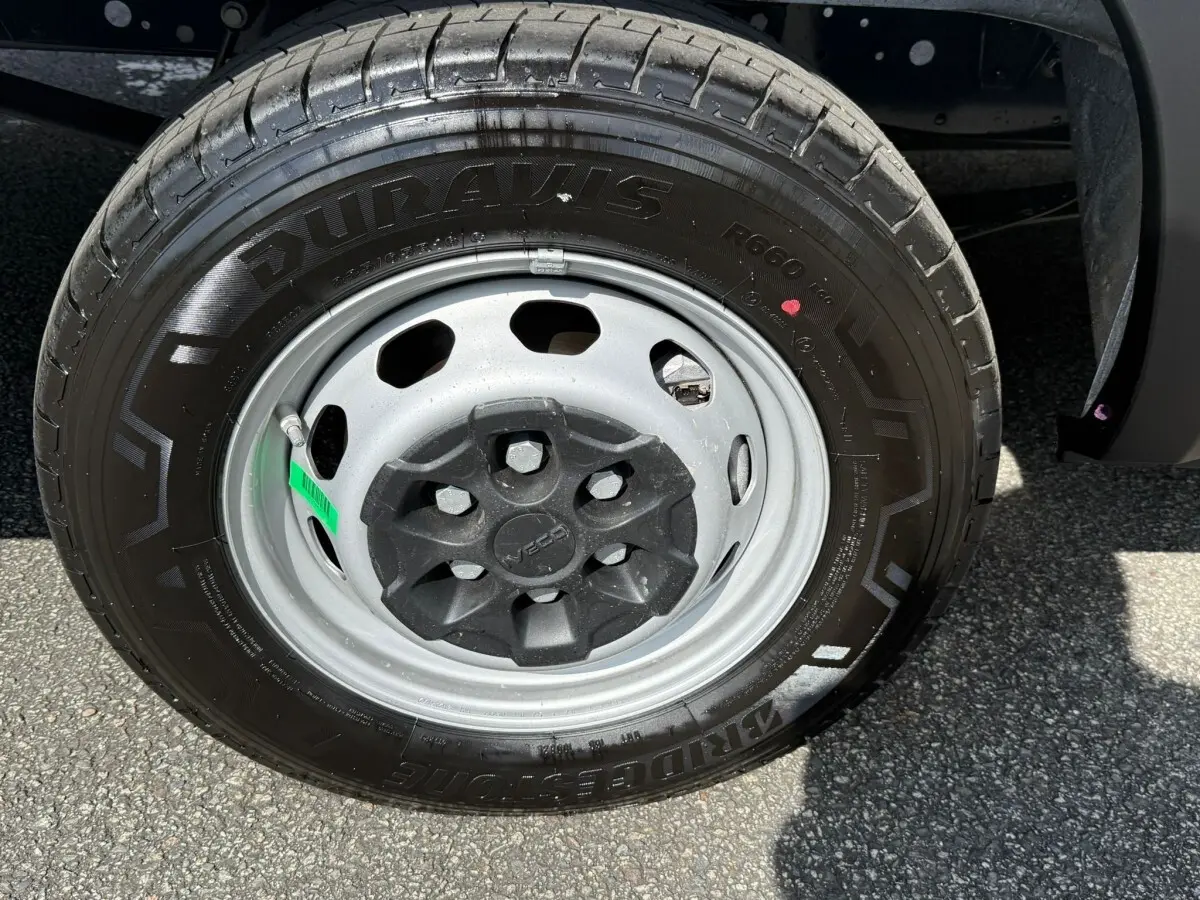 Gros plan sur la roue avant droite d’un Iveco Daily blanc, mettant en valeur la jante acier et le pneu Bridgestone Duravis.