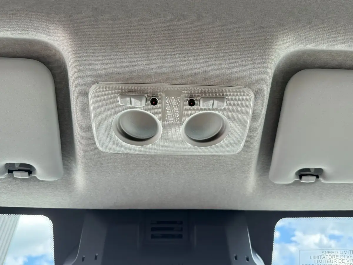 Vue intérieure du plafond avant de l'IVECO Daily blanc 2026, montrant les lampes de lecture et les pare-soleil.