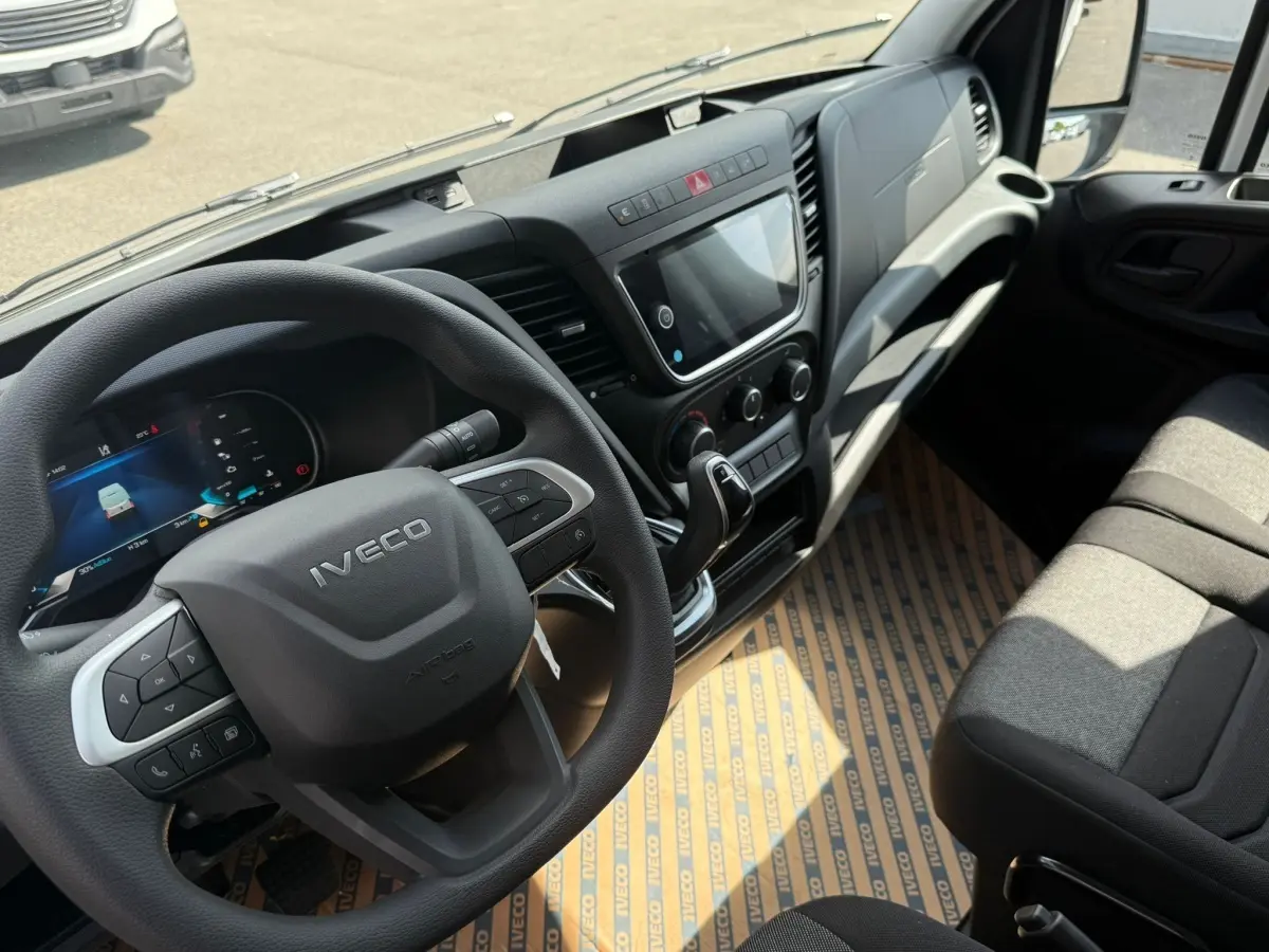 Vue intérieure de l’IVECO Daily 35S18 2026, montrant le volant, tableau de bord et siège passager en tissu gris.