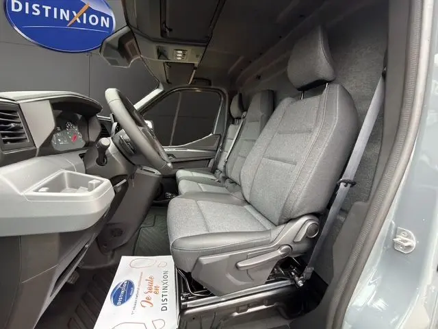 Vue intérieure côté conducteur du Renault Master gris urbain, montrant la banquette passager tissu chiné gris avec surpiqûres bleues.