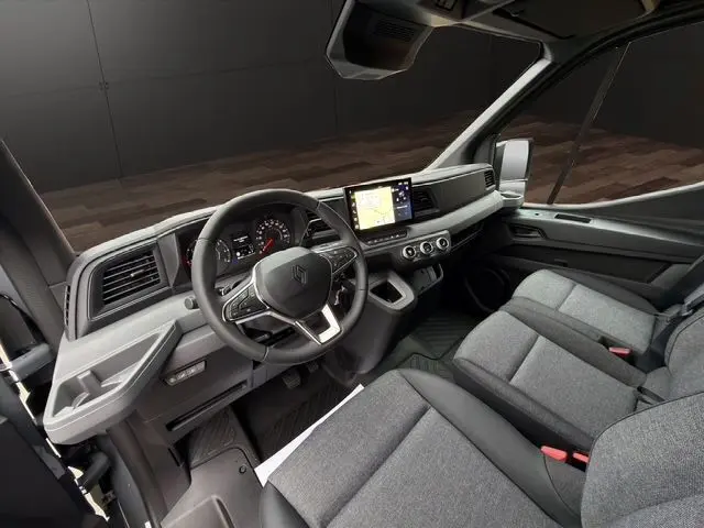 Vue intérieure côté conducteur du Renault Master 2025, tableau de bord moderne avec écran tactile et sièges tissu gris.