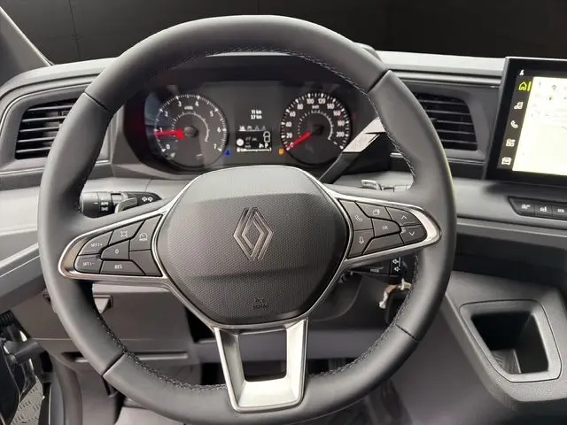 Vue rapprochée du volant noir avec logo Renault et tableau de bord digital du Master gris urbain 2025.