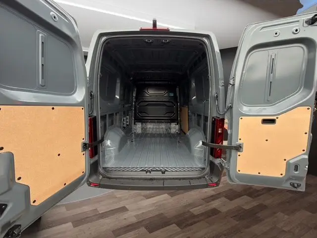 Vue arrière ouverte du Renault Master gris urbain, montrant l’espace de chargement vide avec portes arrière tôlées.