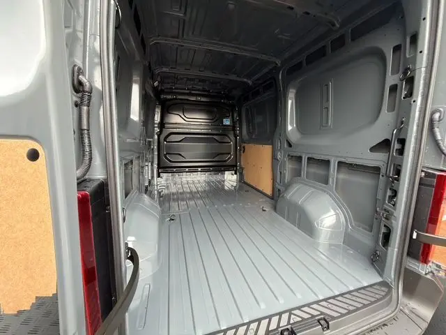 Vue intérieure arrière du Renault Master gris urbain, montrant l'espace de chargement vide avec cloison tôlée noire.