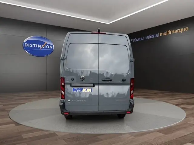 Vue arrière d'un Renault Master gris urbain avec portes arrière tôlées et feux verticaux LED, en showroom.