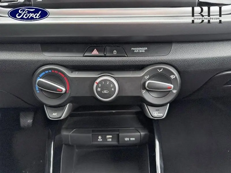 Vue rapprochée du tableau de bord central de la Kia Rio 2018 avec commandes manuelles de climatisation et boutons noirs.