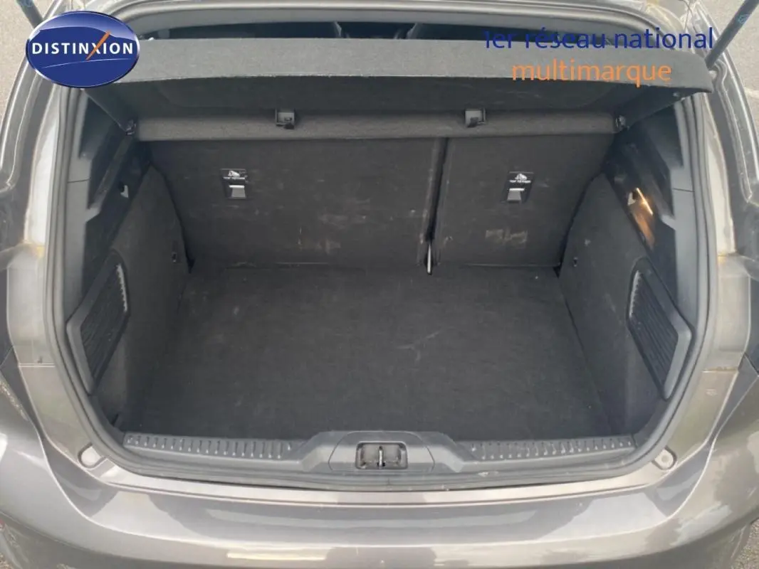 Coffre ouvert vu de l'arrière d'une Ford Focus gris foncé 2024, avec intérieur spacieux et tapis noir.