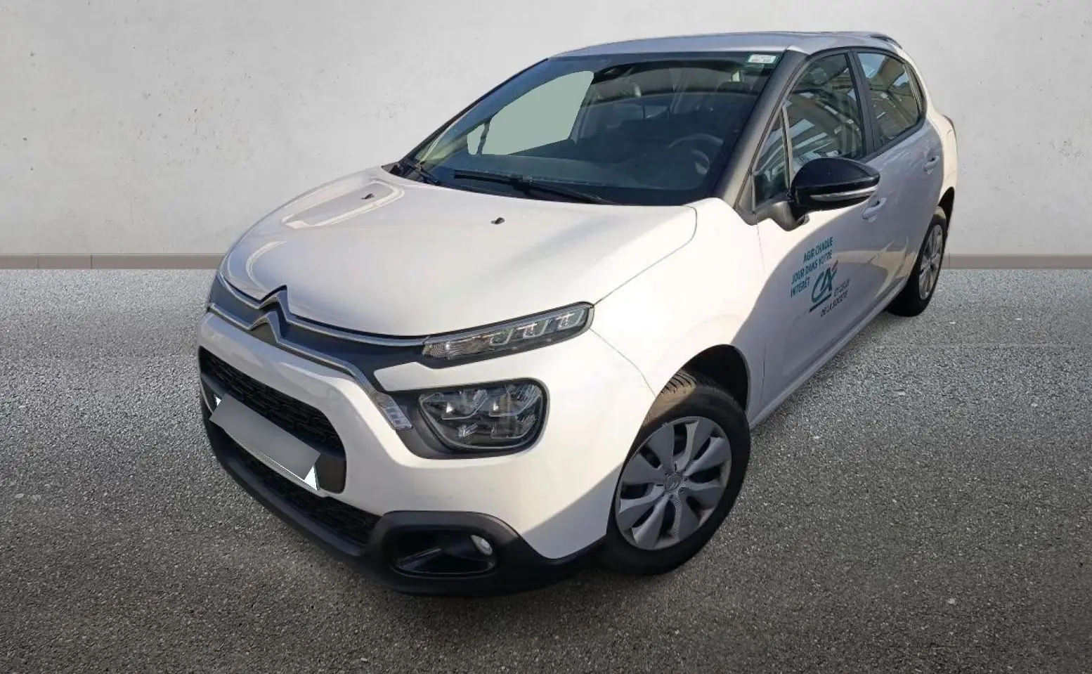 Citroën C3 blanc vue 3/4 avant droit, avec logo sur porte et jantes acier à enjoliveurs.