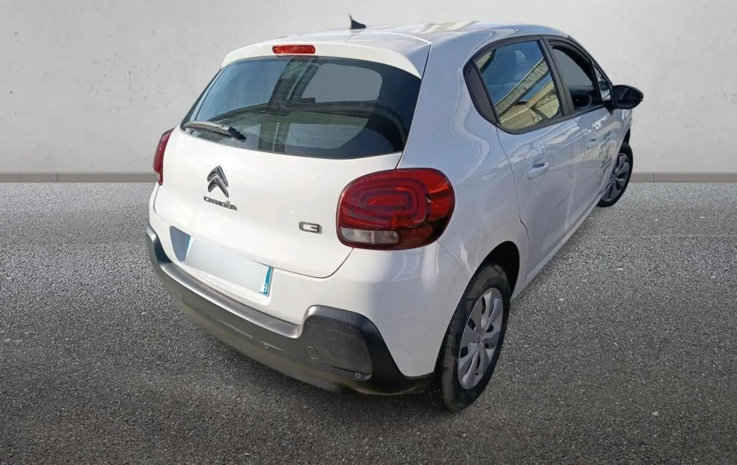 Vue 3/4 arrière droite d'une Citroën C3 blanche de 2021 avec feux arrière arrondis et pare-chocs noir.