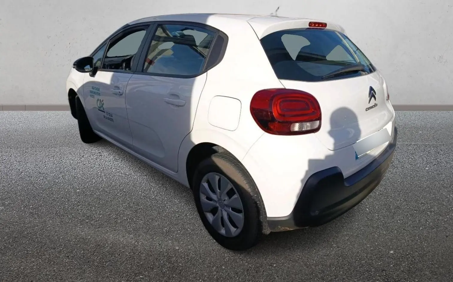 Vue 3/4 arrière gauche d'une Citroën C3 blanche 2021 avec logo et feux arrière rouges bien visibles.