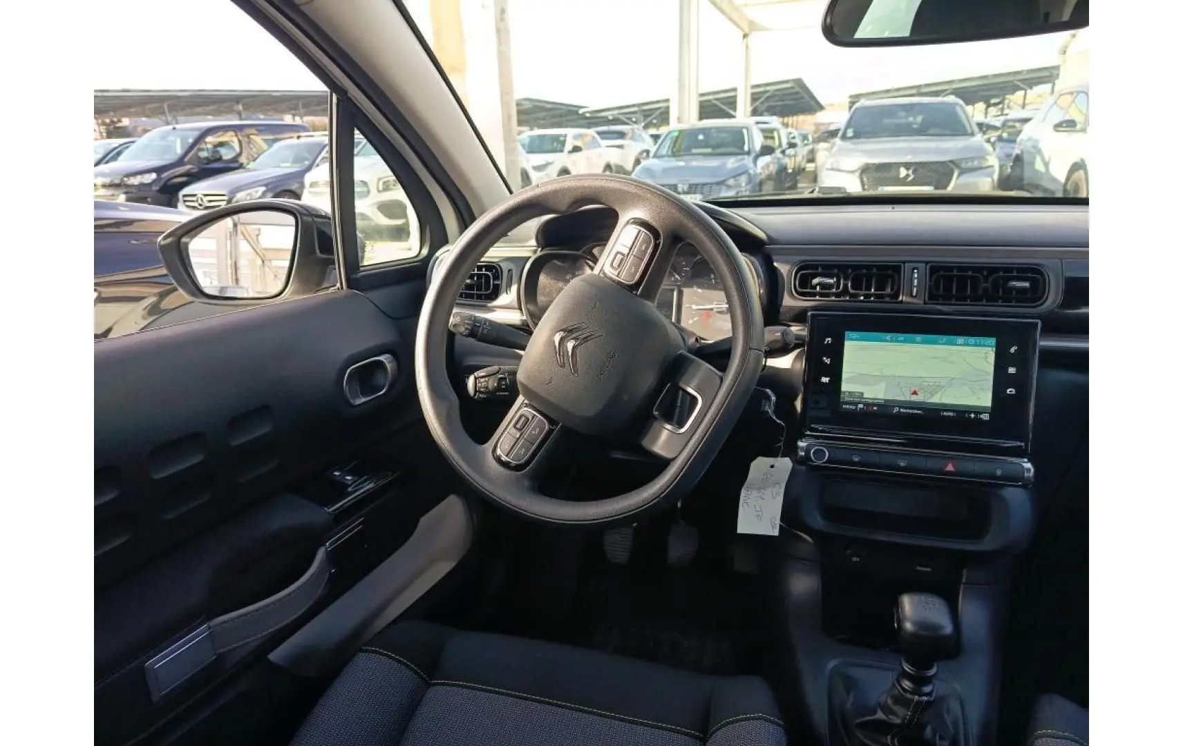 Vue intérieure du poste de conduite de la Citroën C3 2021, tableau de bord noir avec écran GPS tactile et volant multifonction.