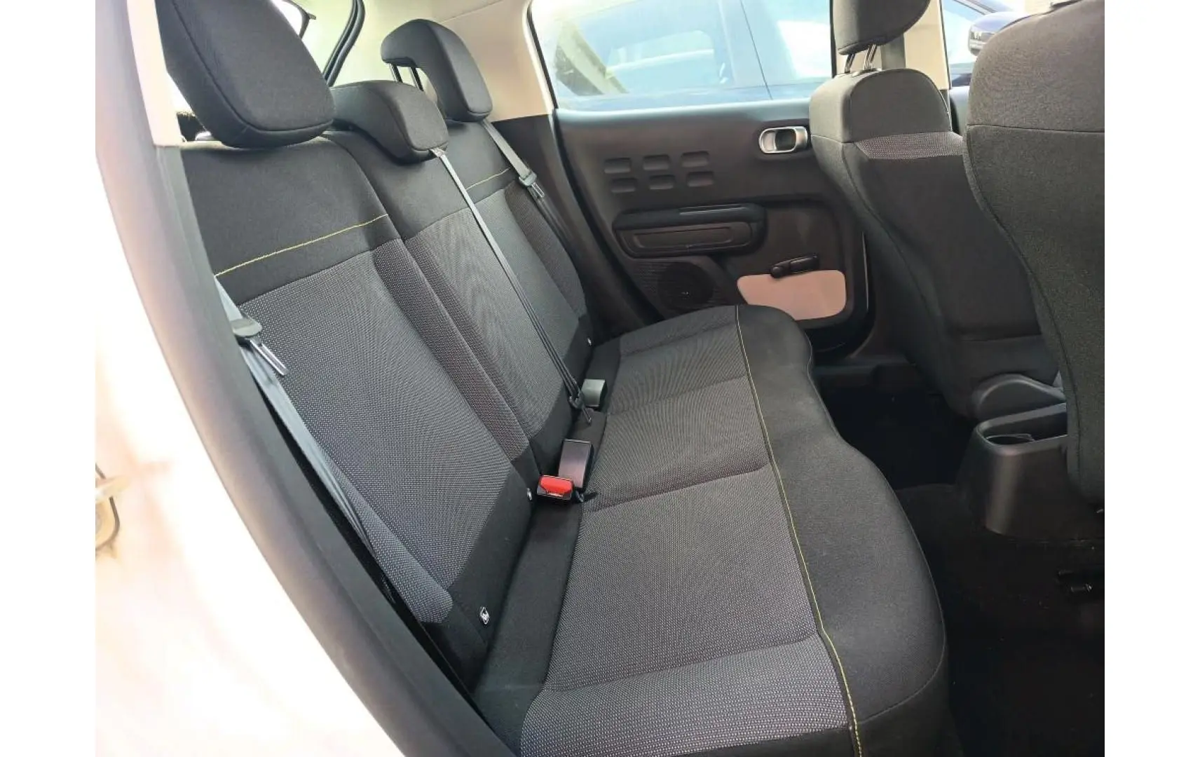 Vue intérieure côté gauche des sièges arrière noirs avec surpiqûres jaunes dans une Citroën C3 blanche de 2021.