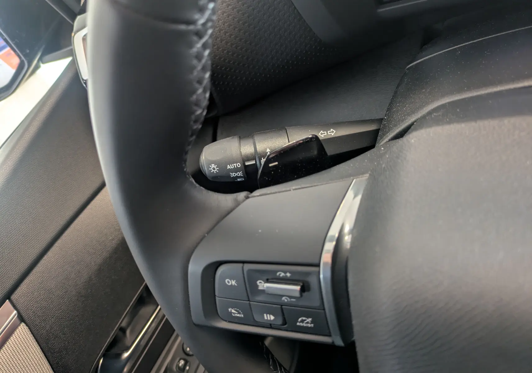 Gros plan sur le volant cuir noir côté gauche du Citroën C4 hybride 2025 avec commandes intégrées et manette de clignotant.