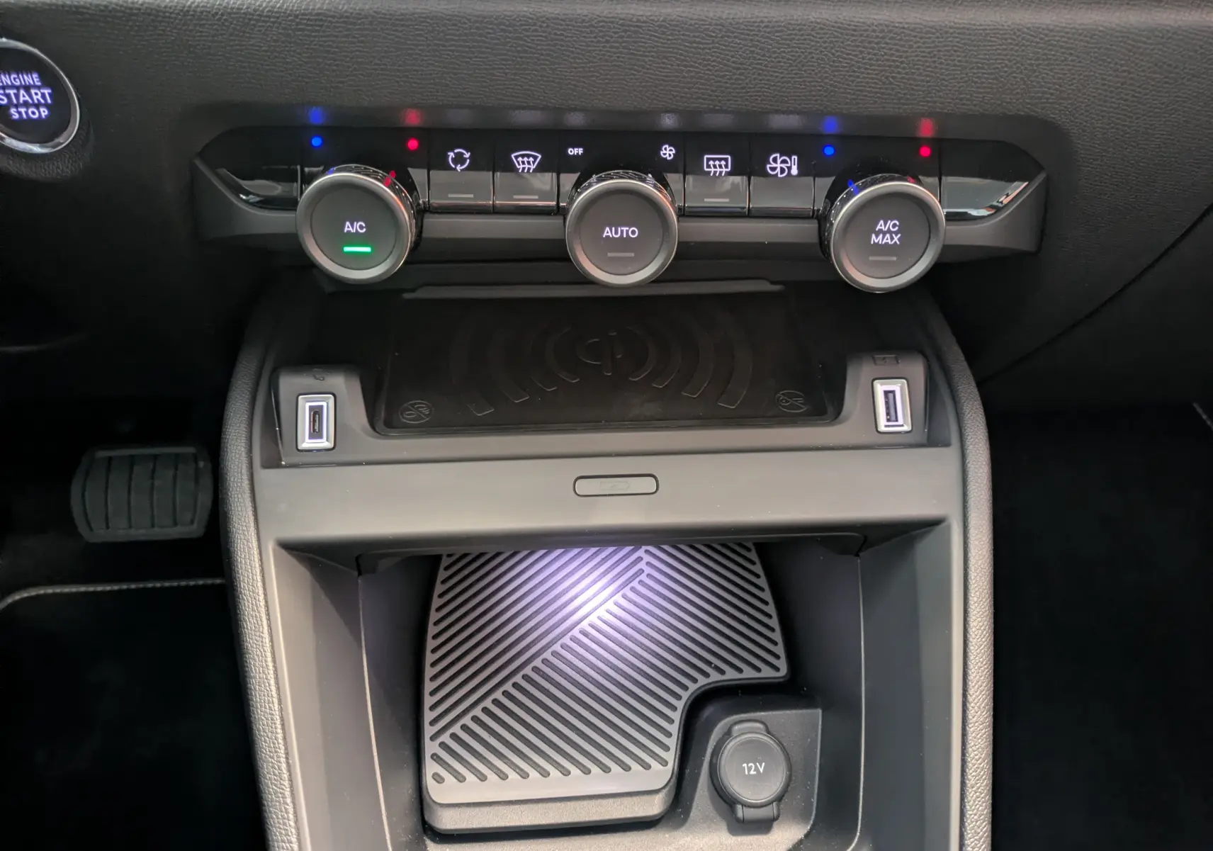 Vue rapprochée de la console centrale noire avec commandes climatisation et chargeur sans fil du Citroën C4 Bleu Eclipse.