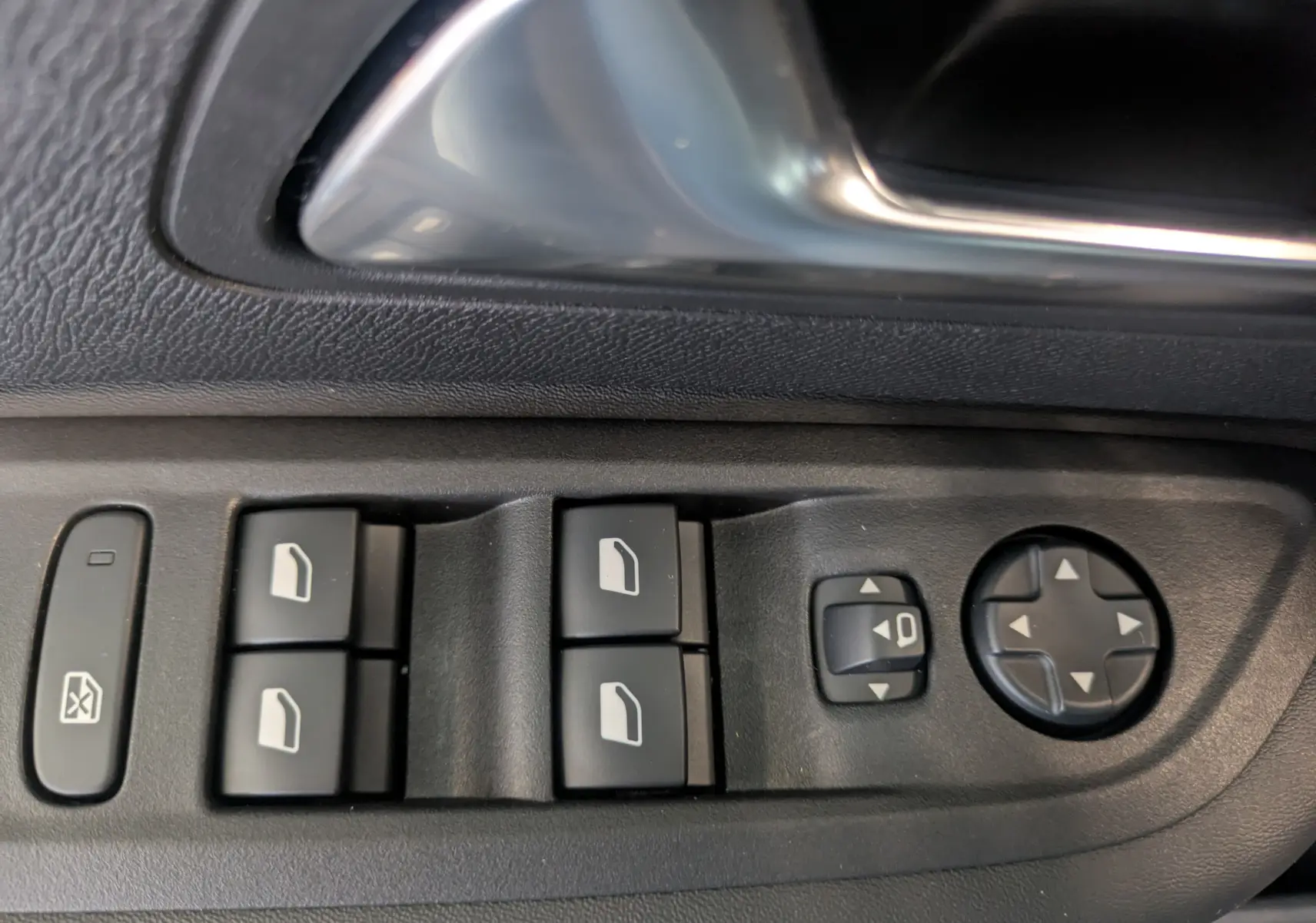 Détail des commandes des vitres et rétroviseurs côté conducteur sur porte intérieure noire d'une Citroën C4 Bleu Eclipse.