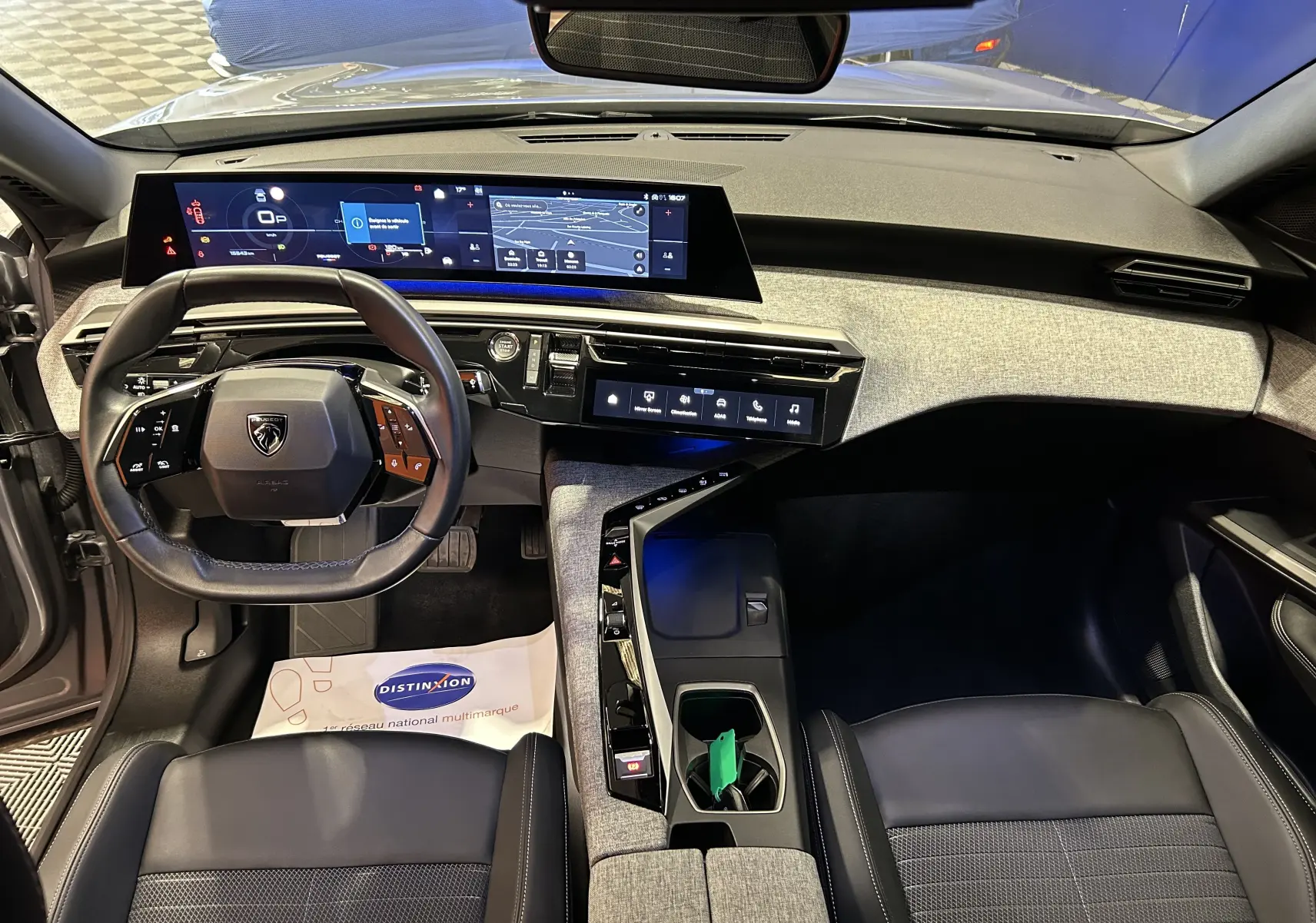 Vue intérieure du poste de conduite du Peugeot 3008 gris Artense 2024, avec tableau de bord numérique panoramique et volant compact.
