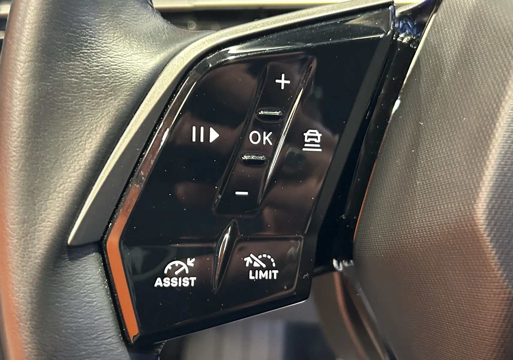 Gros plan sur les commandes noires au volant côté gauche du Peugeot 3008 gris Artense, avec boutons de régulateur et limiteur.