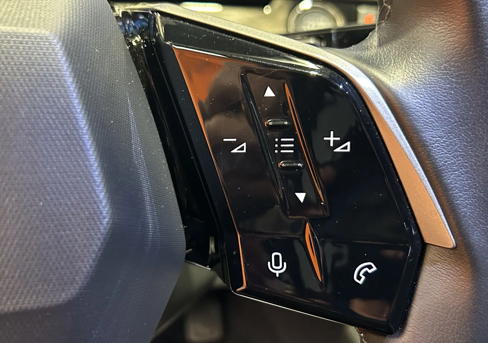 Gros plan sur les commandes noires du volant côté gauche du Peugeot 3008 gris Artense, avec touches volume et appel.