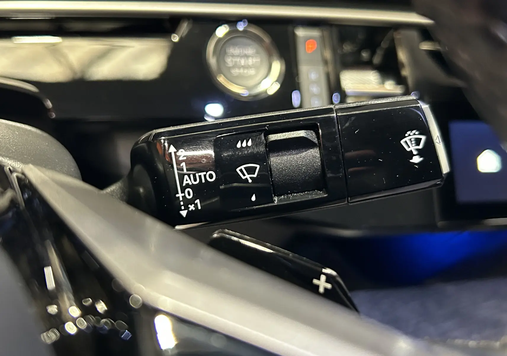 Gros plan sur la commande d’essuie-glace du Peugeot 3008 gris Artense, avec bouton Start/Stop en arrière-plan flou.