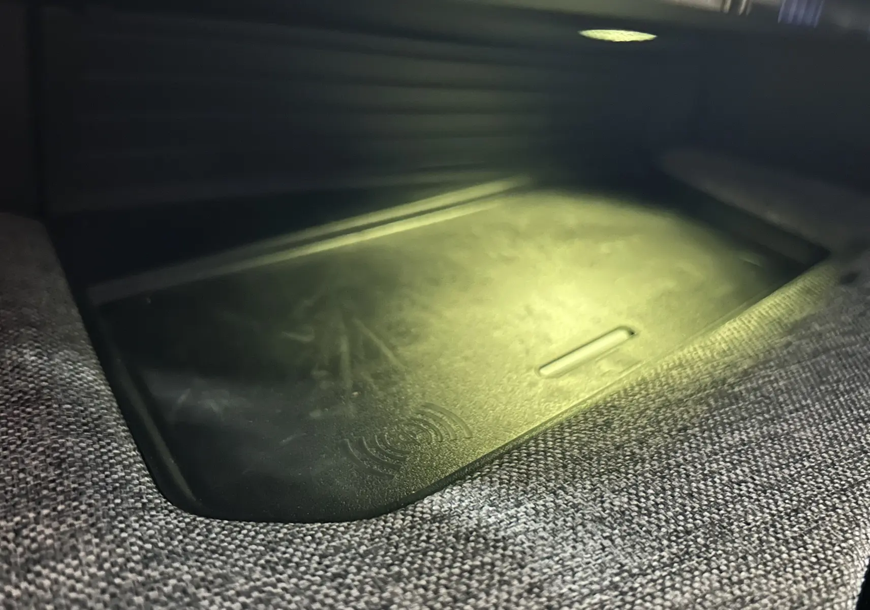 Gros plan sur le chargeur à induction intégré dans l'accoudoir central du Peugeot 3008 gris Artense 2024.