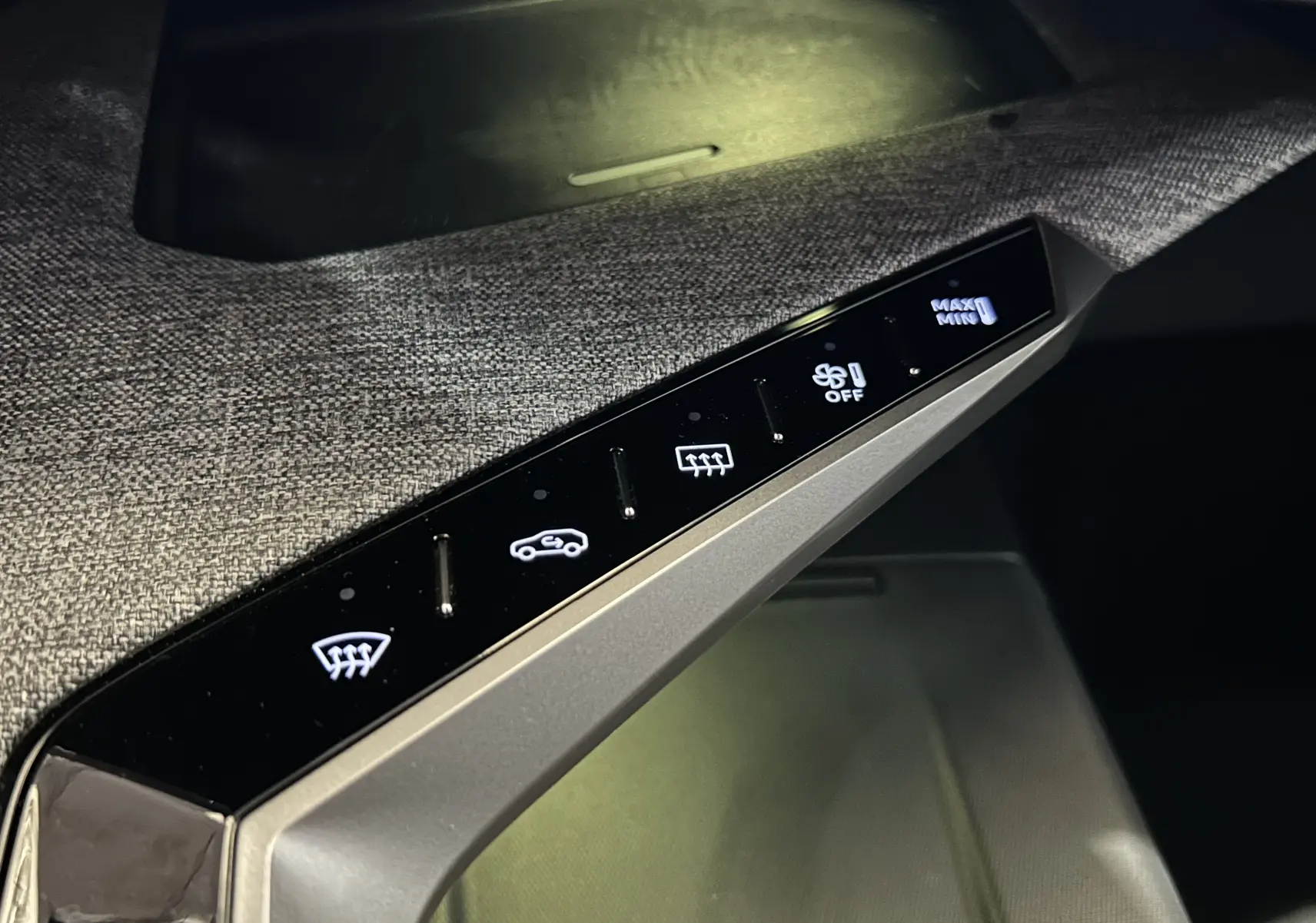 Gros plan sur la console intérieure tactile du Peugeot 3008 III Hybrid 145, avec commandes de climatisation éclairées.