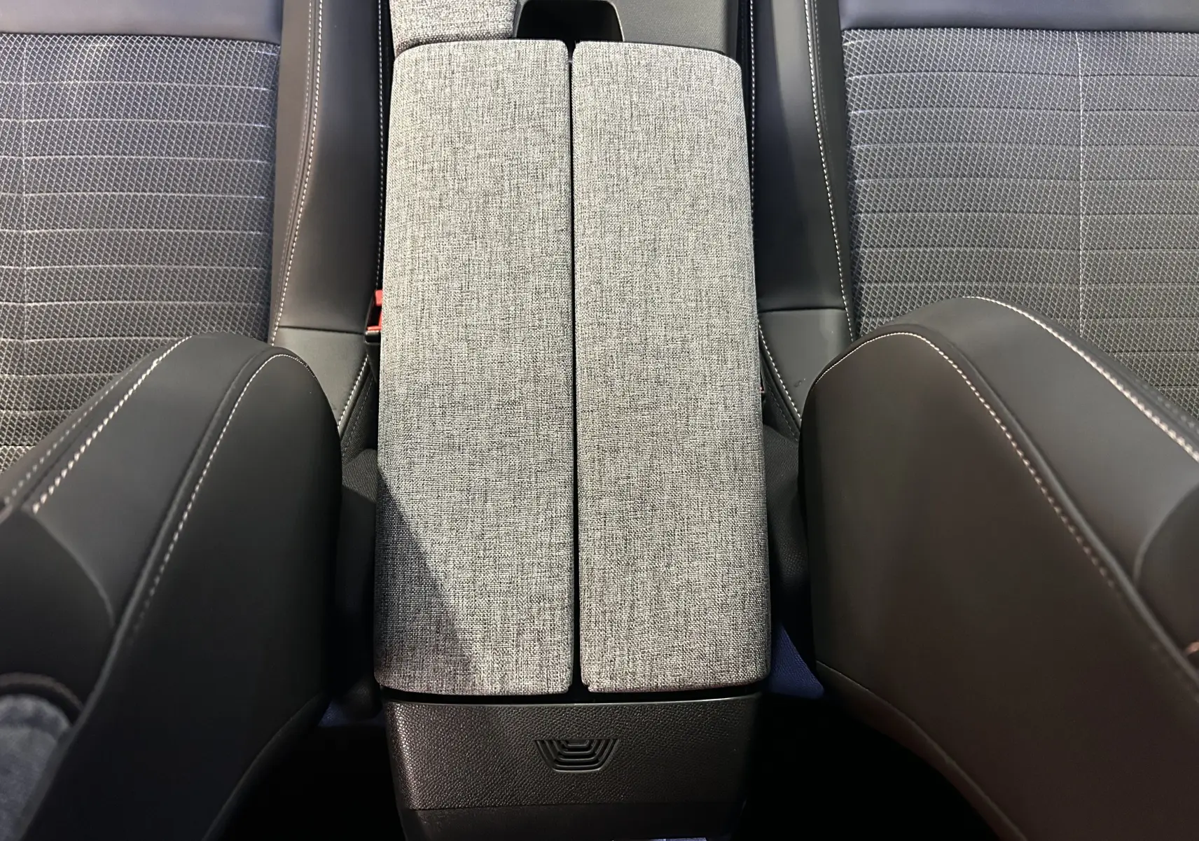 Vue rapprochée de l'accoudoir central gris clair et des sièges tissu gris avec surpiqûres blanches dans un Peugeot 3008 2024.