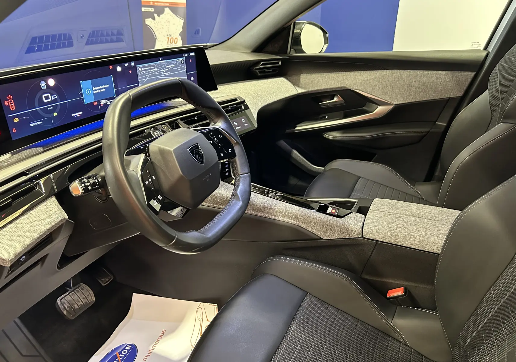 Vue intérieure côté conducteur du Peugeot 3008 hybride 2024, avec i-Cockpit numérique et sellerie cuir/gris clair.