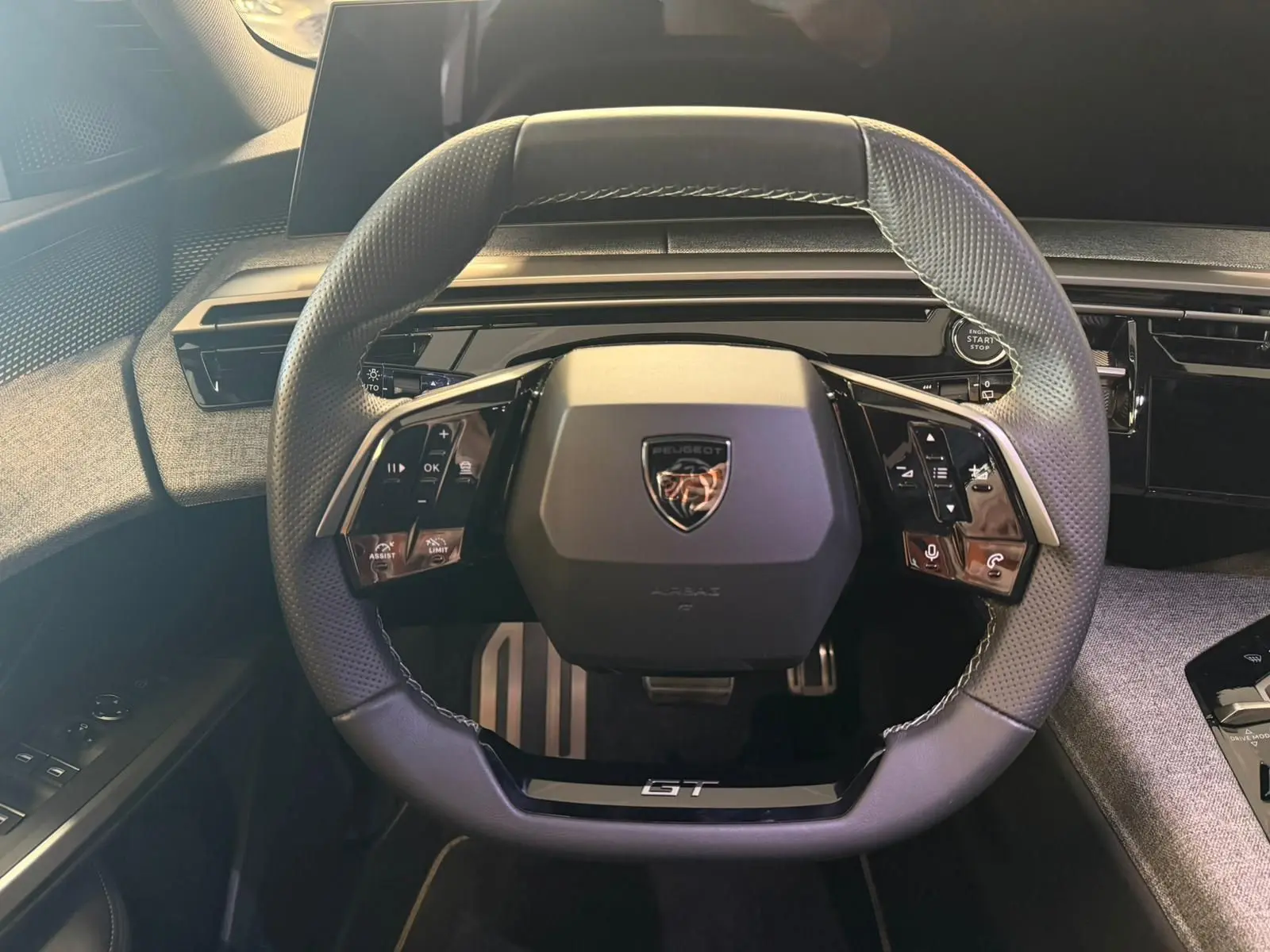 Vue rapprochée du volant GT du Peugeot 5008 Hybrid 145, avec commandes intégrées et surpiqûres blanches.