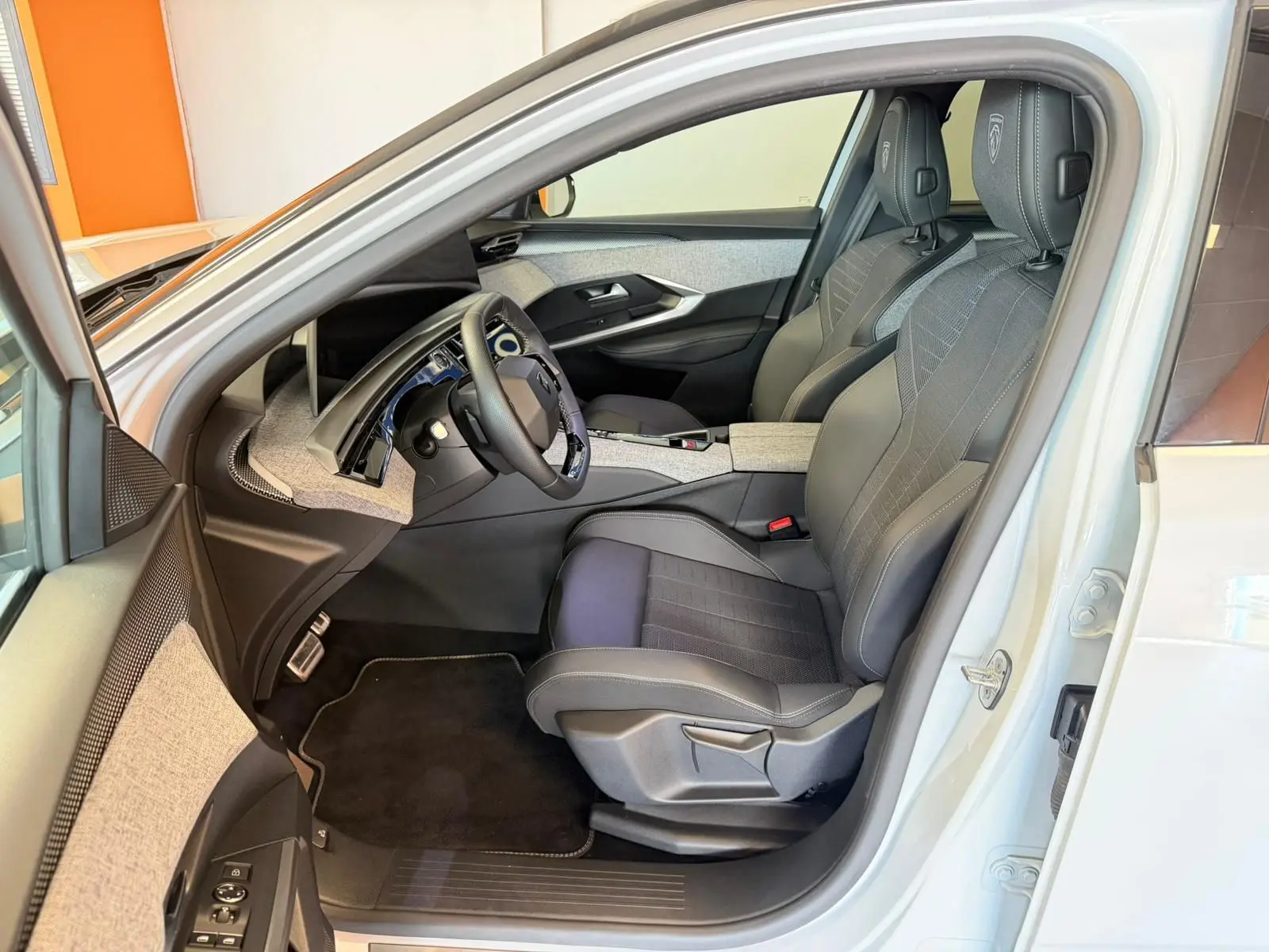 Vue intérieure côté conducteur du Peugeot 5008 Hybrid blanc Okenite, sièges tissu/tep gris avec surpiqûres Iced Clay.