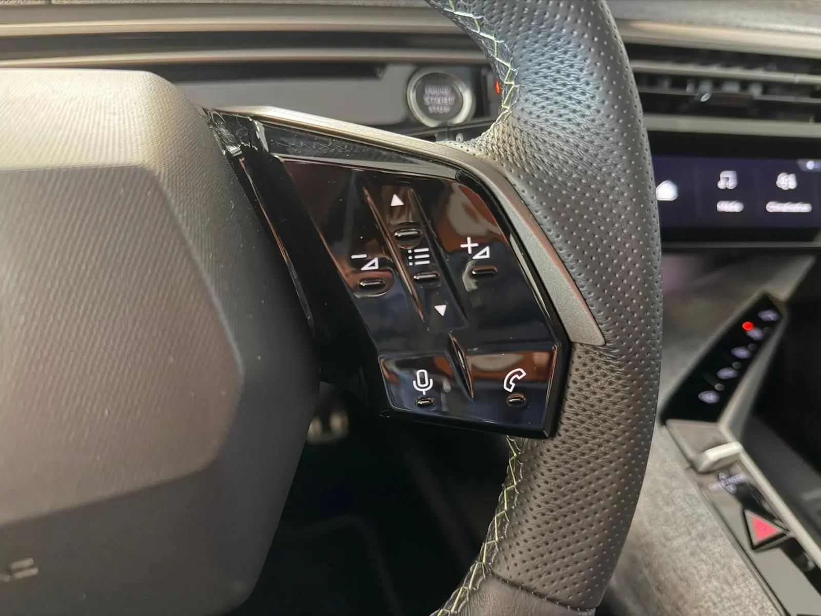 Gros plan sur les commandes au volant à droite du Peugeot 5008 Hybrid 145 e-DCS6 GT, intérieur noir avec surpiqûres claires.