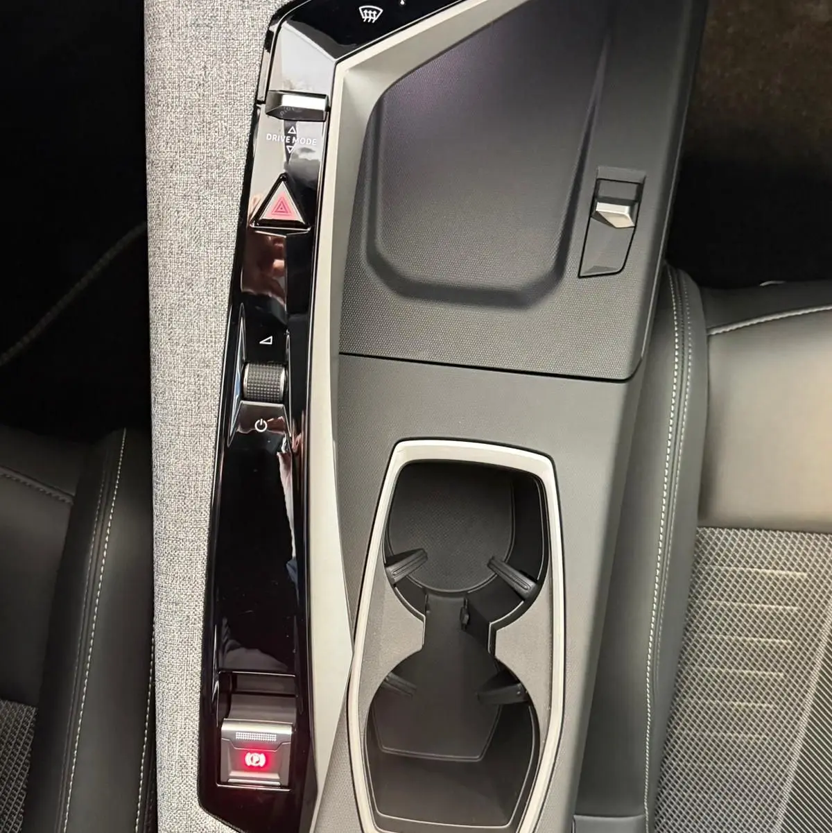 Vue plongeante sur la console centrale du Peugeot 5008 Hybrid 145 GT, avec accoudoir tissu gris et porte-gobelets noirs.