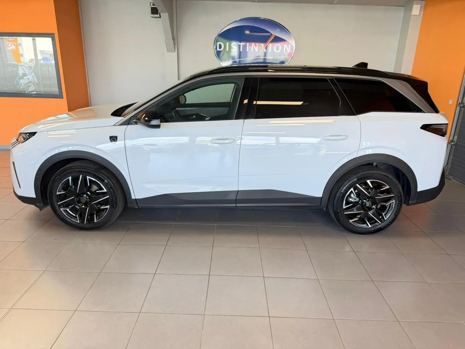 Peugeot 5008 Hybrid 145 e-DCS6 GT blanc Okenite toit noir, vue profil côté gauche en intérieur showroom.