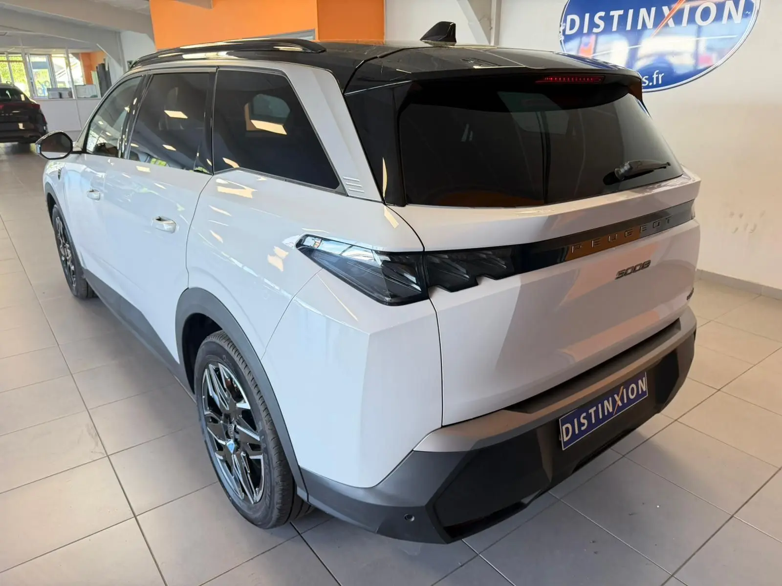 Peugeot 5008 Hybrid blanc Okenite avec toit noir, vue 3/4 arrière droit, jantes alliage 19 pouces visibles.