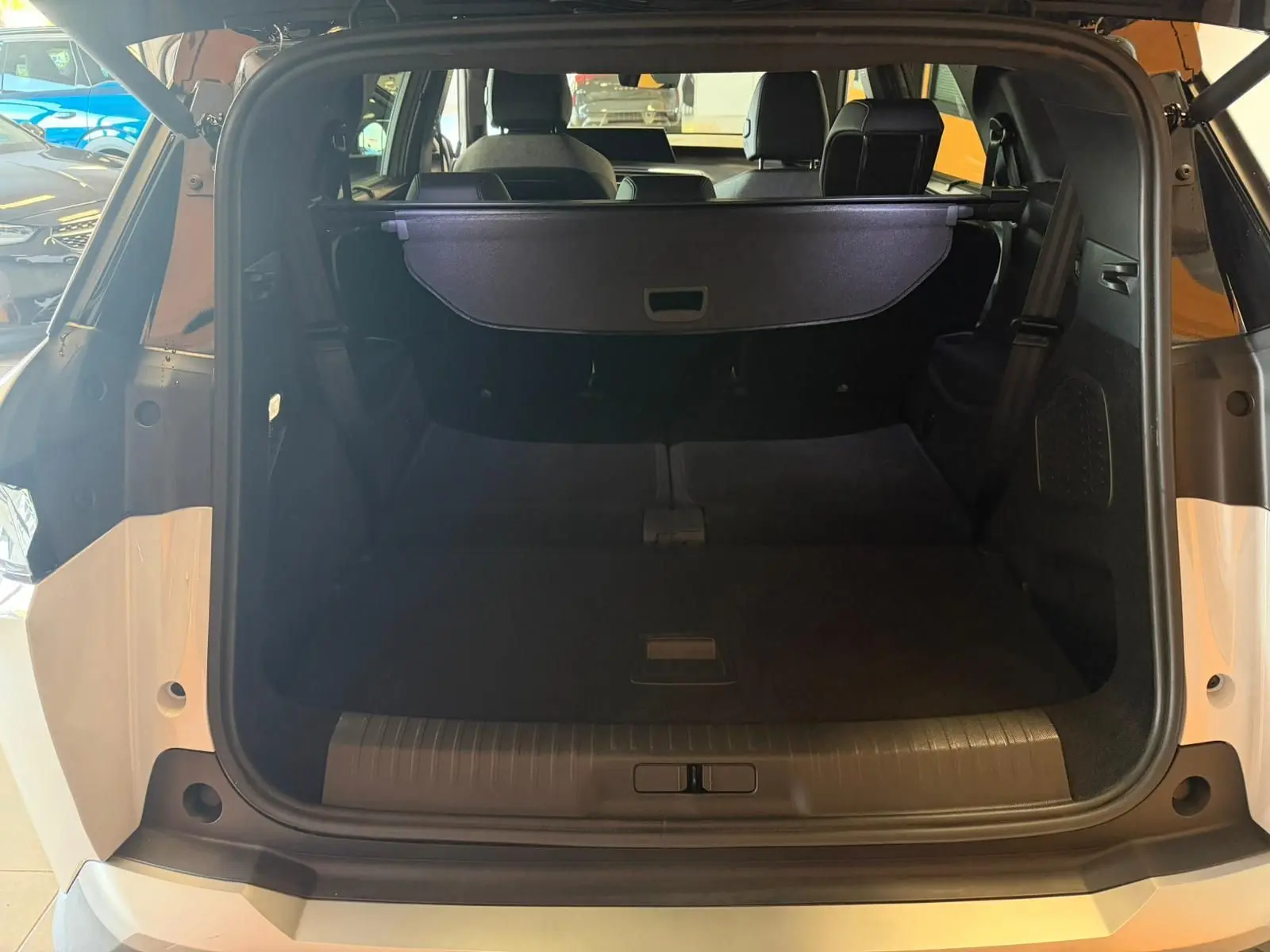 Vue arrière ouverte du coffre du Peugeot 5008 Hybrid 145 e-DCS6 GT blanc Okenite avec toit noir, montrant l'espace de chargement.