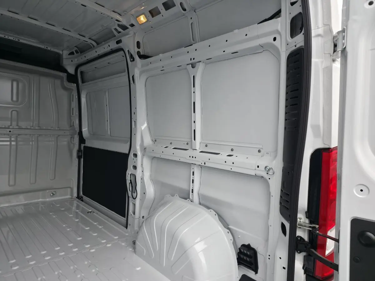 Vue intérieure arrière du fourgon Peugeot Boxer blanc, montrant l'espace de chargement tôlé et la porte ouverte.