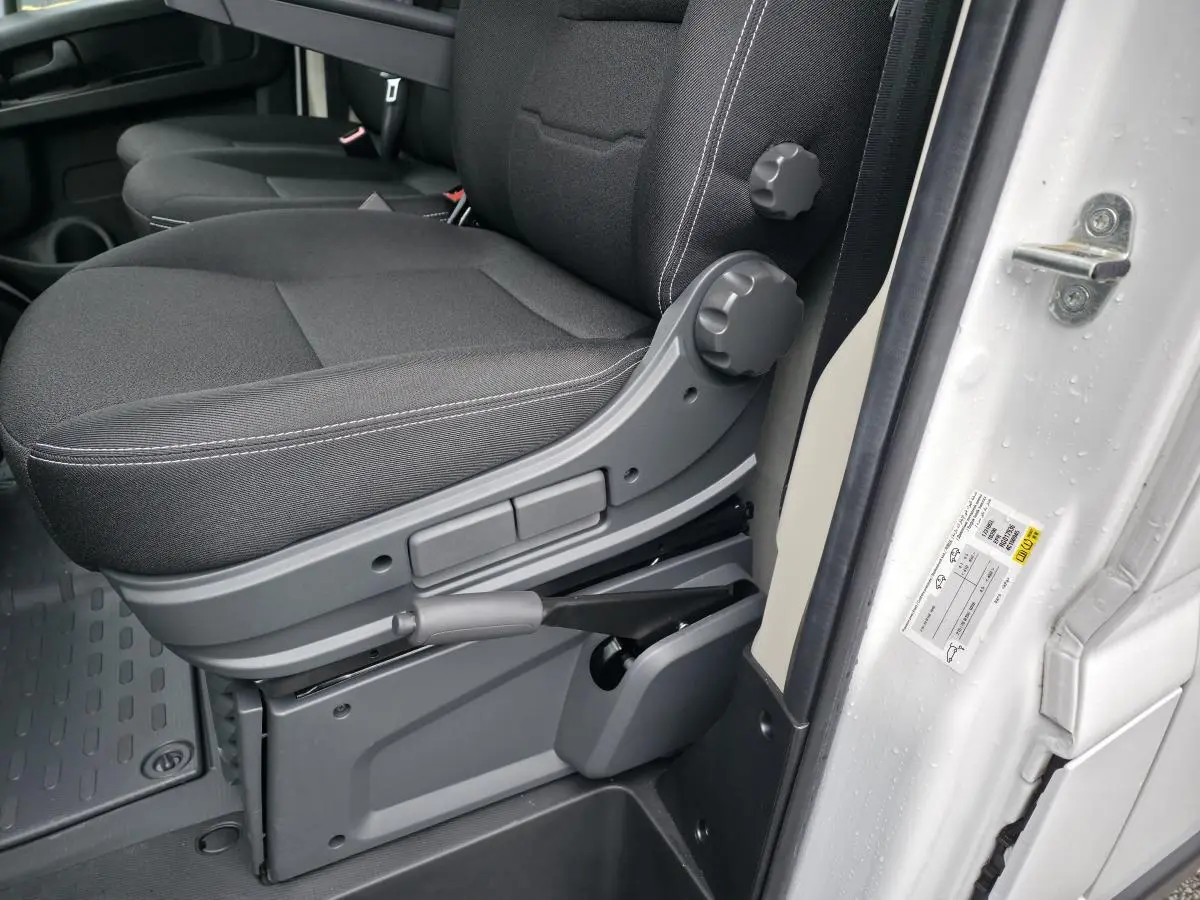 Gros plan sur la banquette biplace noire côté conducteur du Peugeot Boxer Fourgon blanc, avec réglages manuels visibles.