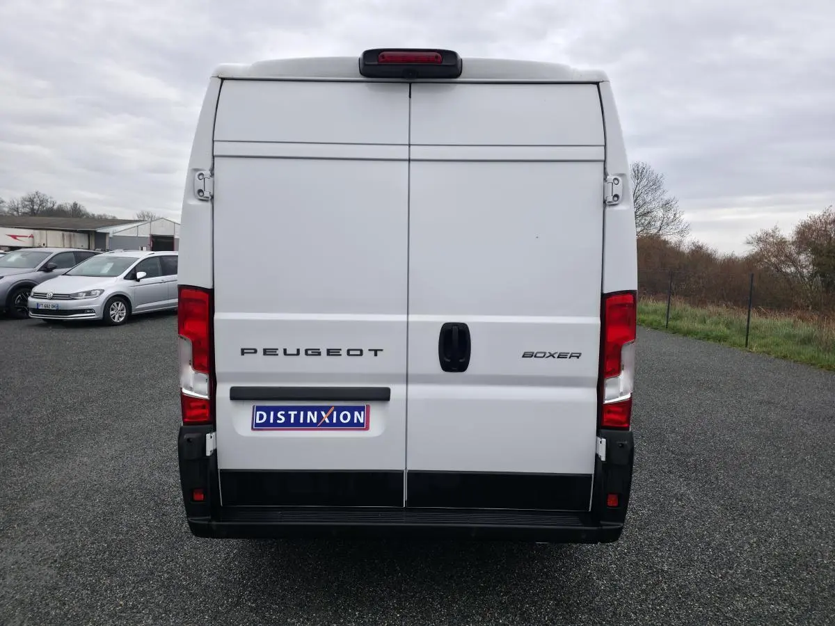 Vue arrière d'un Peugeot Boxer Fourgon blanc avec portes battantes et feux rouges visibles.