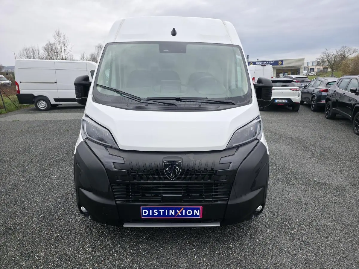 Vue avant d'un Peugeot Boxer Fourgon blanc avec calandre noire et logo lion distinctif, sur parking extérieur.