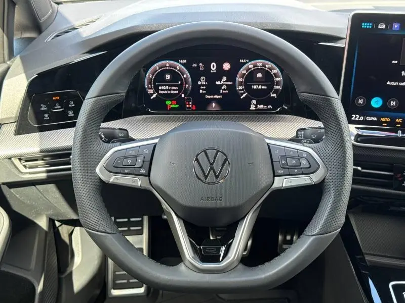 Vue centrée du volant cuir multifonction d’une Volkswagen Golf gris lunaire avec tableau de bord numérique et écran tactile.