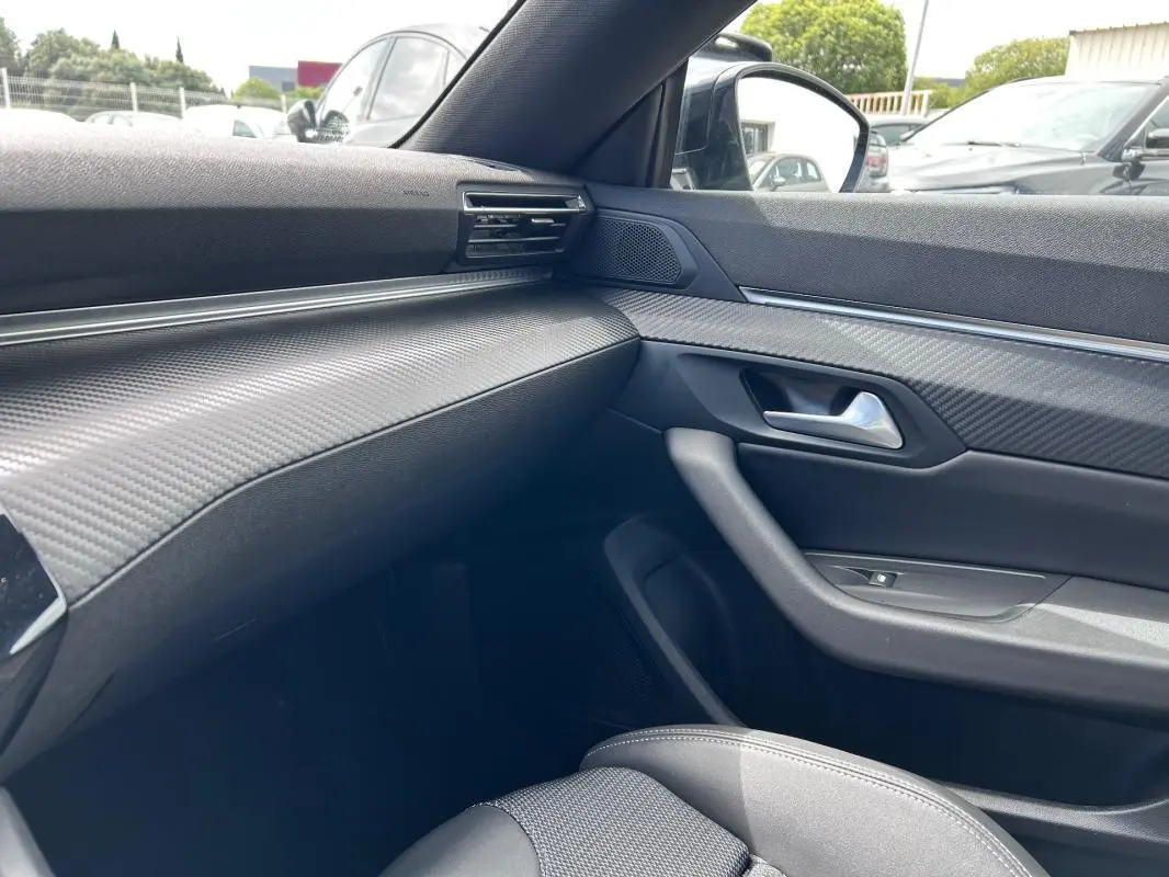 Intérieur côté passager du Peugeot 508 Hybrid 225 e-EAT8 Allure 2024, avec tableau de bord noir texturé et porte en carbone.