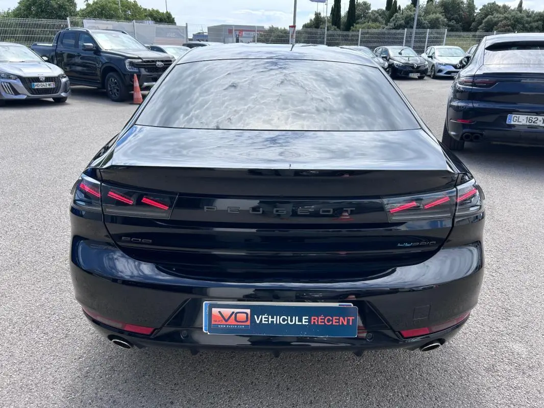 Vue arrière d'une Peugeot 508 Hybrid 225 noire de 2024, avec feux LED distinctifs et double sortie d'échappement.