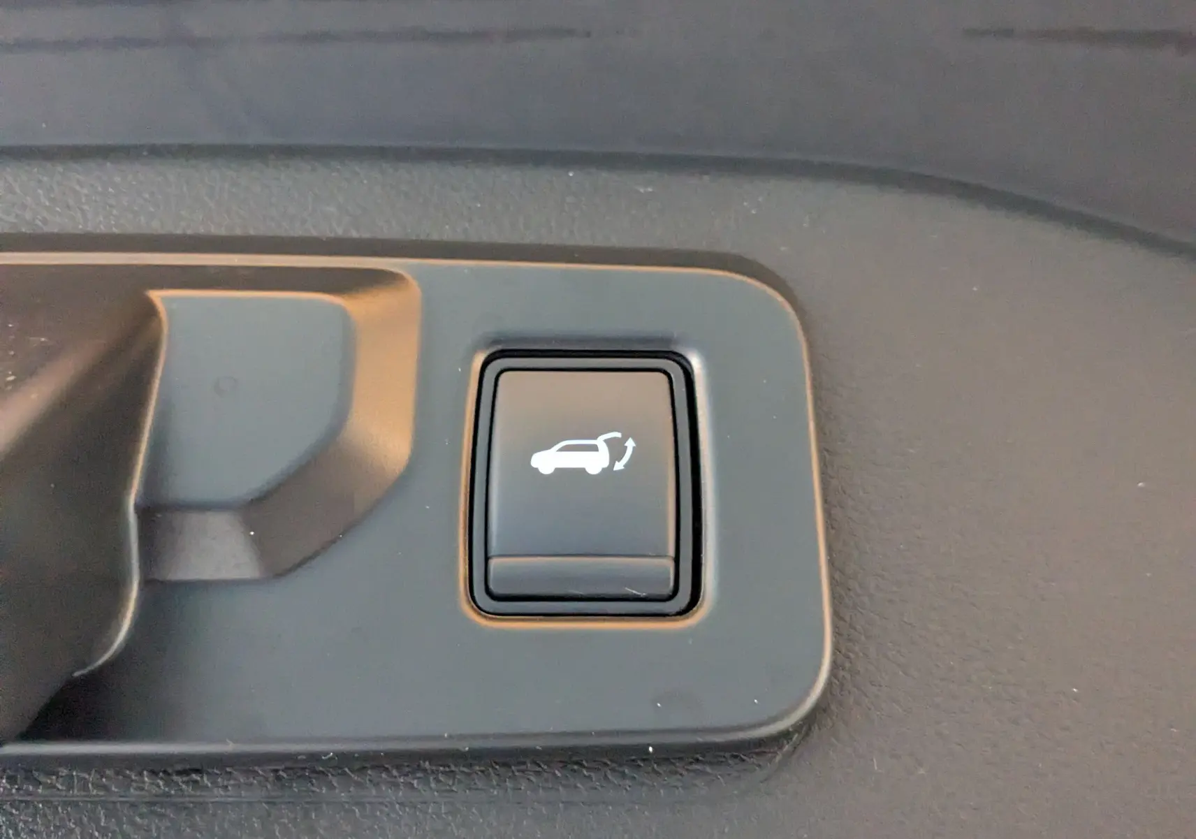 Bouton intérieur noir avec symbole blanc d'ouverture de hayon, détail du Renault Espace VI E-Tech Full Hybrid 2025.