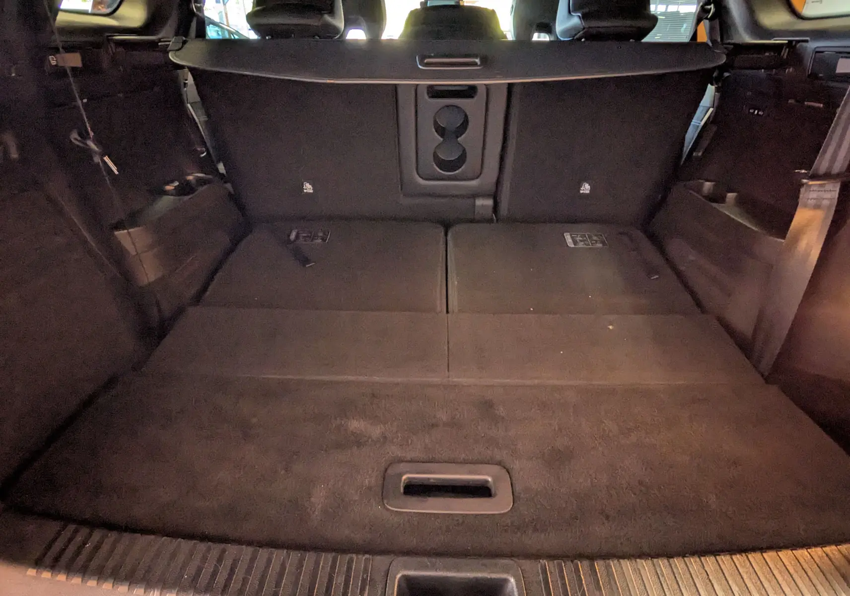 Coffre arrière ouvert en vue intérieure du Renault Espace VI noir étoile avec sièges arrière rabattus et plancher plat.