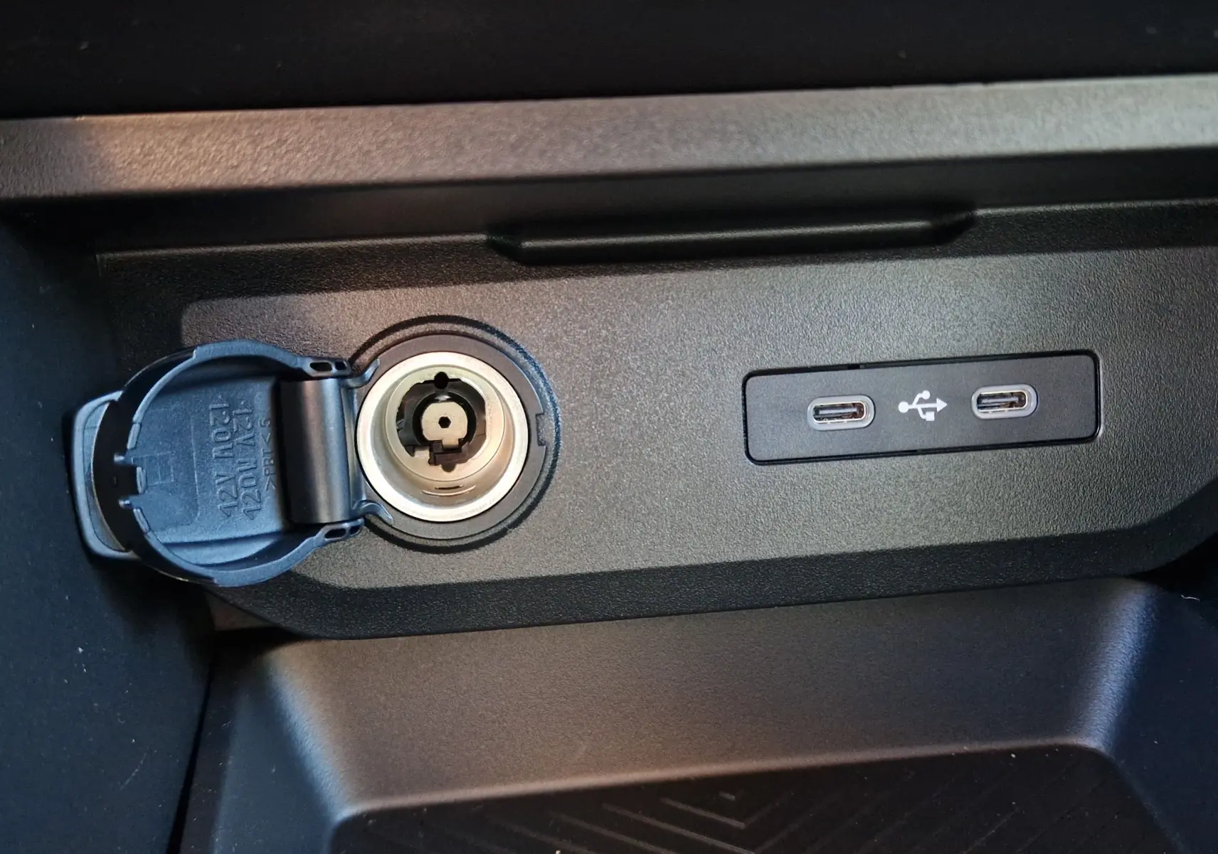Vue rapprochée de la prise 12V et des deux ports USB-C intégrés dans la console centrale du Dacia Duster Vert Cèdre 2026.