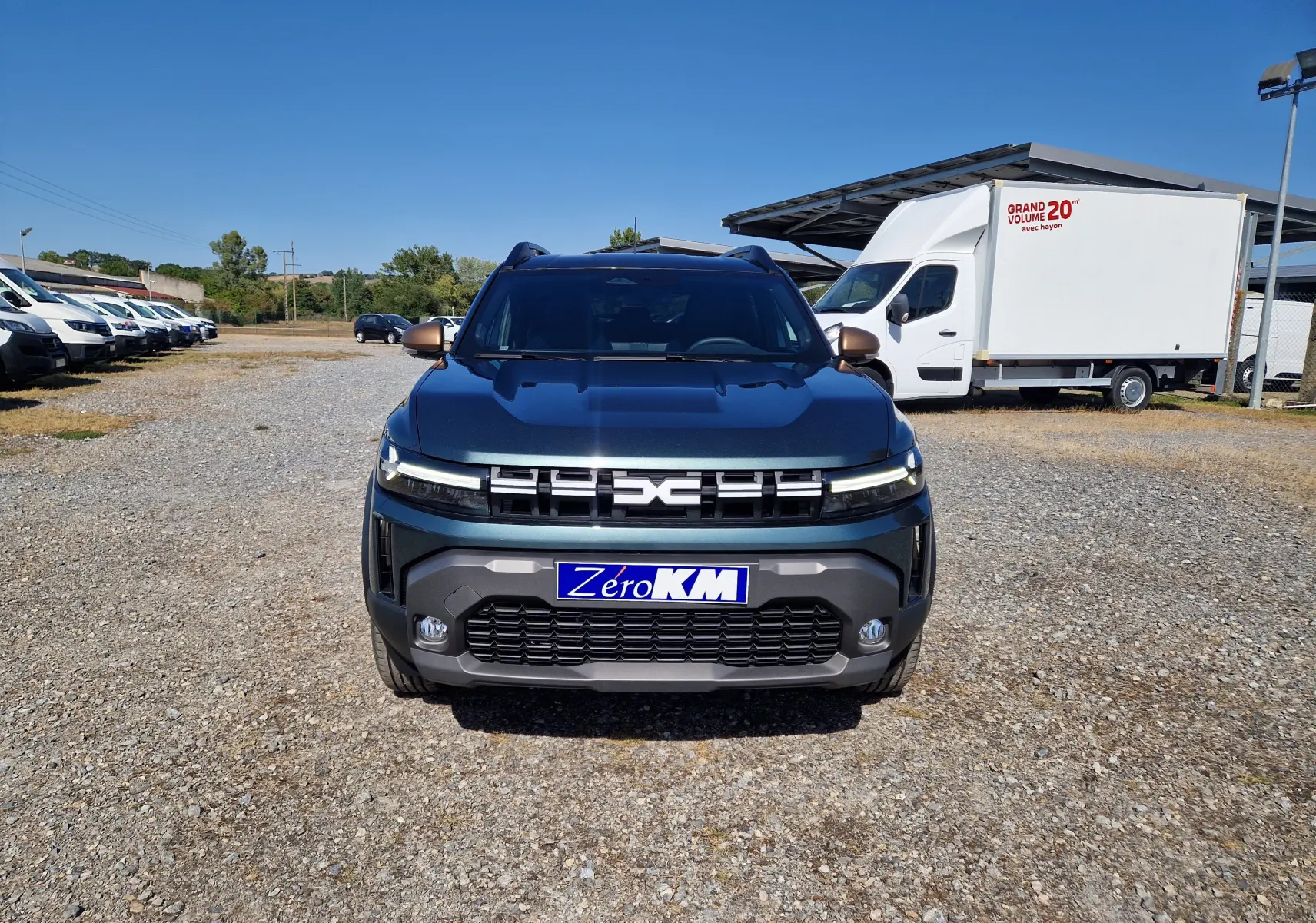 Vue frontale d'un Dacia Duster 1.8 Hybrid 155 Extreme vert cèdre, avec calandre moderne et plaque "Zero KM".
