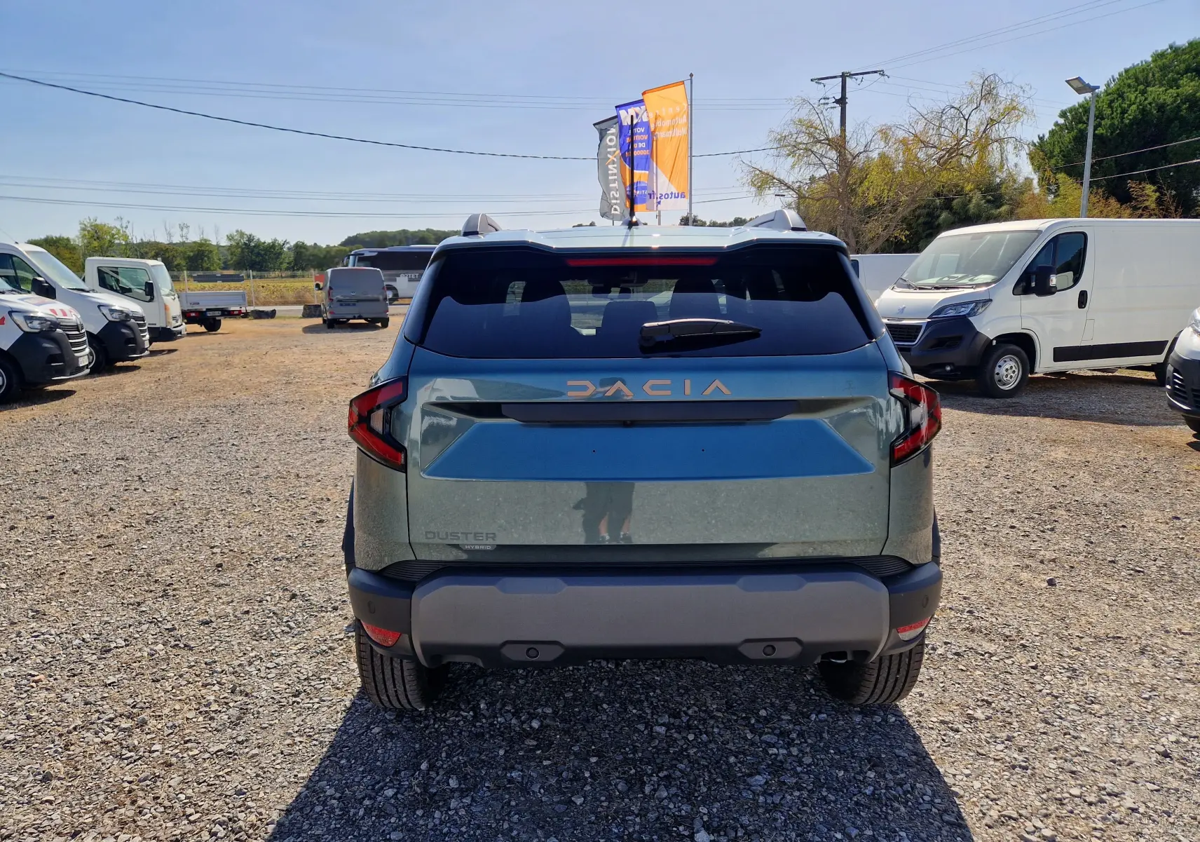 Vue arrière d'un Dacia Duster 1.8 Hybrid 155 Vert Cèdre, avec logo DACIA en relief et feux arrière anguleux.